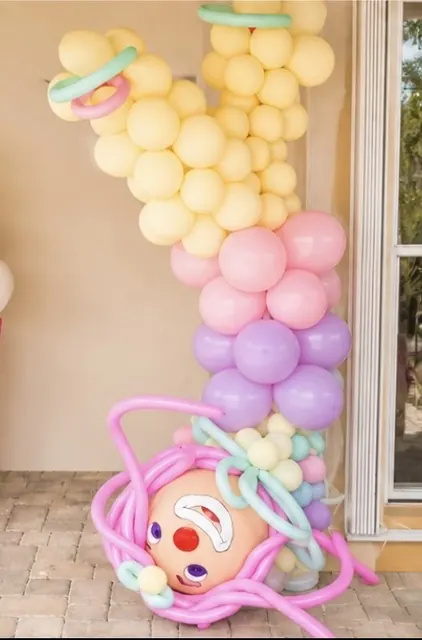Pastel balloon column topped with a playful clown balloon sculpture